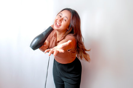 Young Asian woman holding a hair dryer and using the hair dryerの写真素材