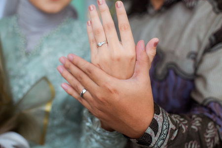 The bride and groom exchange rings at the wedding. A husband and wife put rings on each other's fingers. Holding a wedding ring. Precious metal jewelry for married couples.の写真素材