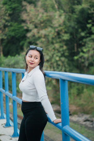 Young Asian woman wearing white casual clothes is posing outdoors showing her fashion and ootd. Stylish Asian woman with sunglasses outdoors.の写真素材