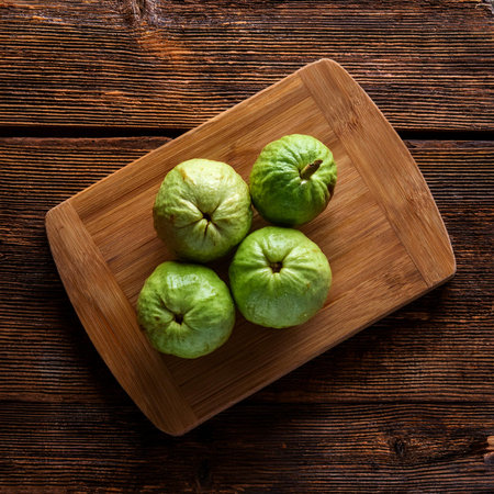 guava fruit on a wooden cutting board, isolated against a wooden backgroundの写真素材