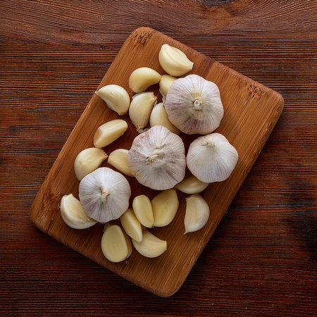 white Garlic cloves on a wooden cutting board, isolated against a wooden backgroundの写真素材