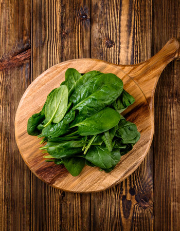 spinach on a wooden cutting board, isolated against a wooden backgroundの写真素材