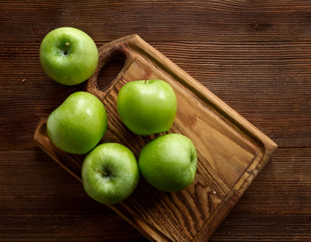 Green apples in wooden cutting board isolated on wooden background