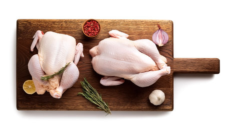 Raw chicken on wooden cutting board isolated on white backgroundの写真素材