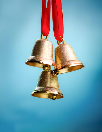 golden bells with red ribbons hanging from them floating or flying isolated on light blue backgroundの写真素材