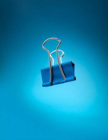 Binder clips floating or flying isolated on light blue backgroundの写真素材