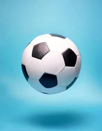 White and black soccer ball floating or flying isolated on light blue backgroundの写真素材