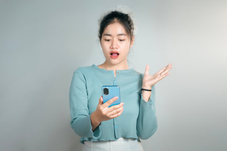 Surprised Asian woman looking at her smartphoneの写真素材