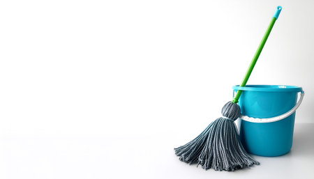 A blue bucket with a green handle sits next to a mop on side position provides copy space for text....