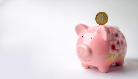 pink flowered piggy bank with coin on side position provides copy space for text. background concept isolated whiteの写真素材