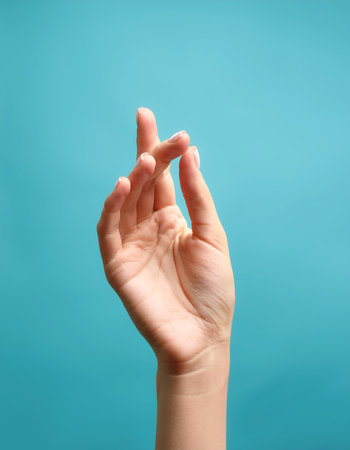Close up Female hand holding something isolated on light blueの写真素材