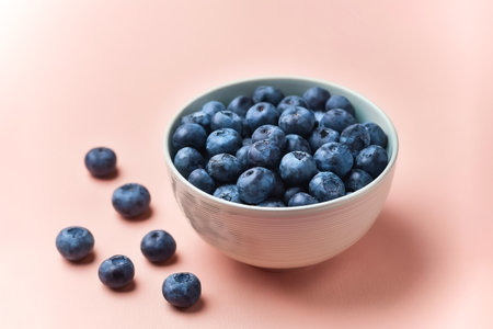 Blueberries in bowl with its fruit scattered isolated on pastel backgroundの写真素材