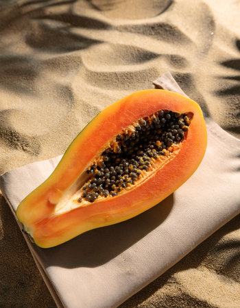 papaya fruit arranged on a cloth mat in the sandの写真素材