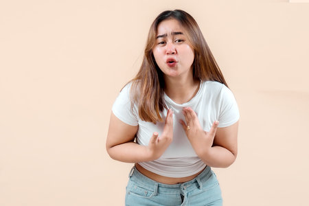 A young woman with a concerned expression, gesturing with her hands as if explaining something, set...