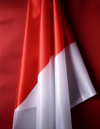 Indonesian flag waving in the wind on side position provides copy space for text isolated dark red backgroundの写真素材