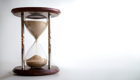 A classic hourglass filled with sand marking the passage of time on side position provides copy...