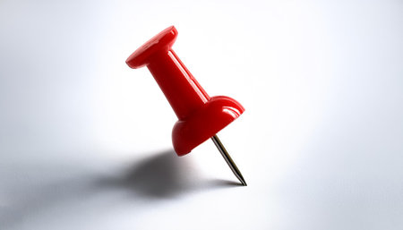 A single bright red push pin with a metallic needle on side position provides copy space for text. background concept isolated whiteの写真素材