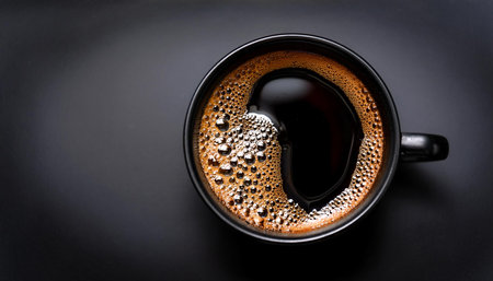 Hot black coffee in black ceramic cup Top view of a freshly brewed cup of black coffee, with bubbles...