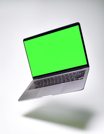 Laptop with green screen floating or flying isolated white backgroundの写真素材