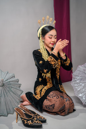 Asian woman in traditional Javanese attire poses gracefully with closed eyes and a peaceful smile. Her calm, meditative expression reflects elegance, cultural richness, and inner serenity.の写真素材