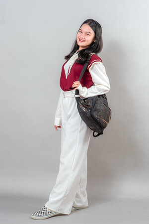 Young woman with a wide, cheerful smile and bright eyes looking directly at the camera. Her positive expression and relaxed pose are ideal for youthful advertising visuals.の写真素材