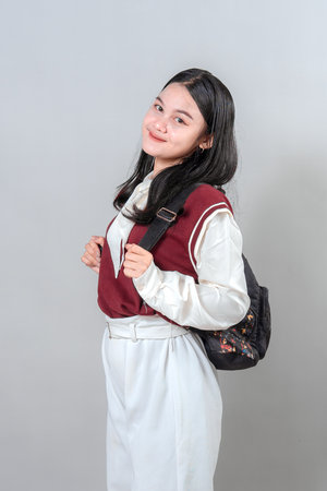 Smiling young woman wearing a backpack, looking confident and content with a soft expression. Ideal for educational, lifestyle, or promotional advertising in modern visual campaigns.の写真素材