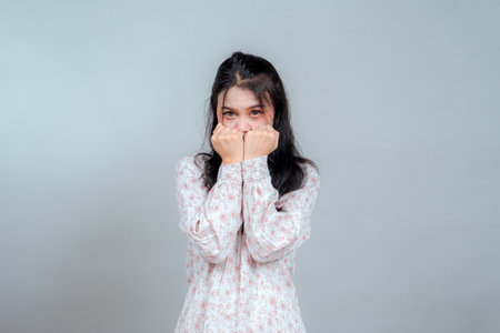Portrait of a young Asian woman looking directly at the camera with a shy and nervous expression,...