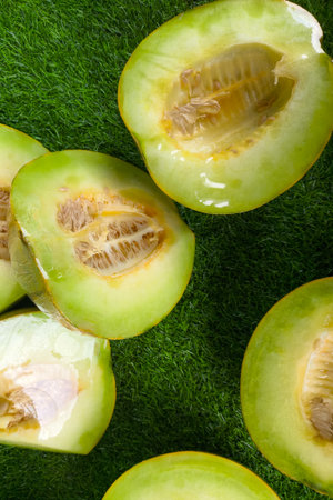 Freshly cut green melons displayed on artificial grass at a traditional market. The juicy texture, seeds, and vibrant color highlight the freshness of tropical fruits.の写真素材