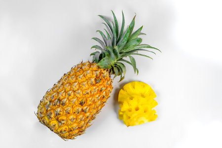 Fresh ripe pineapple with green crown and peeled slices on white background. Tropical exotic fruit...