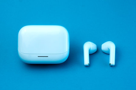 A stylish pair of wireless earbuds with a closed charging case on a blue background. The compact and...