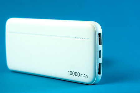 A white 10000mAh portable power bank with dual USB ports and a Type-C input on a blue background....