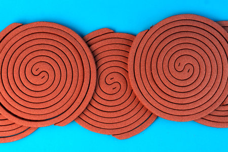 Multiple brown mosquito coils in a spiral pattern on a blue background. Traditional insect repellent designed to keep mosquitoes away for indoor and outdoor protection.の写真素材