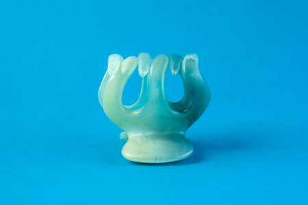 A translucent plastic hair claw clip with a spring mechanism on a bright blue background. The close-up shot highlights its curved design, ideal for securing hair in place stylishly.の写真素材