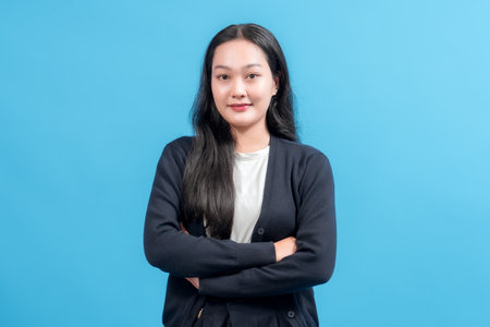 Confident young woman with arms crossed, wearing casual outfit, standing against bright blue background. Perfect for business, lifestyle, self-assurance, positivity, and personal branding concepts.の写真素材