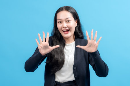 Young woman in casual attire showing a stop gesture with hands on a blue background, conveying emotions like alertness, excitement, or caution with a vibrant and uplifting tone.の写真素材
