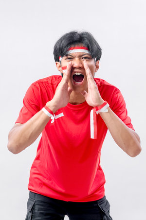 Young Indonesian man shouting with both hands raised to his mouth, showing excitement and spirit...