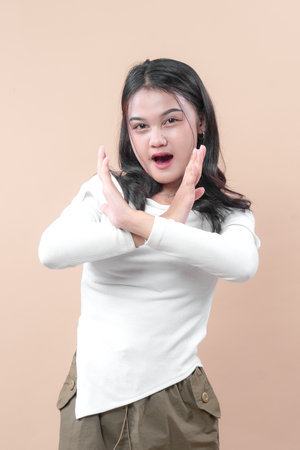 Young Asian woman making an X sign with crossed arms in front of her chest, expressing refusal and confident body language.の写真素材