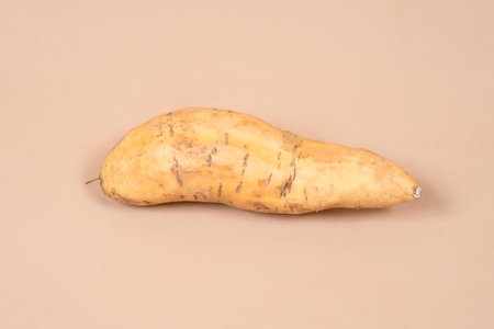 Close-up of Cilembu sweet potato with natural texture on plain background, showcasing its unique shape, earthy surface, and potential as a healthy tropical food ingredient.の写真素材