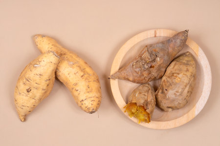 Sweet Cilembu sweet potatoes displayed raw and baked on a wooden plate, showcasing traditional Indonesian food, natural nutrition, and healthy lifestyle.の写真素材