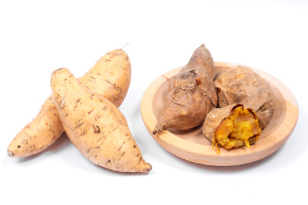 Cilembu sweet potatoes on a white background, showing raw yellow tubers beside roasted ones with caramelized flesh, highlighting natural freshness, nutrition, and organic taste.の写真素材