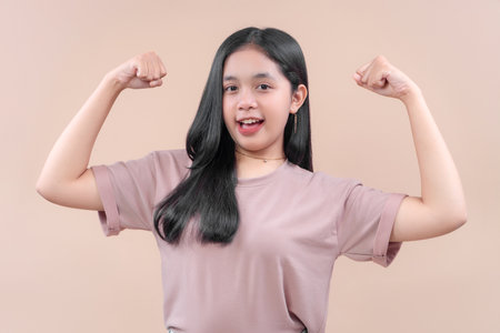 Confident Asian woman in casual modern outfit showing strong arm pose, smiling with cheerful...