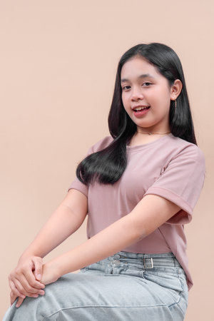Asian woman in casual modern outfit sitting with a confident and cheerful smile, showing natural charm and positive expression, representing youth and lifestyle.の写真素材
