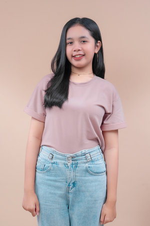 Asian woman with long black hair wearing a pastel casual t-shirt and light blue jeans, smiling...