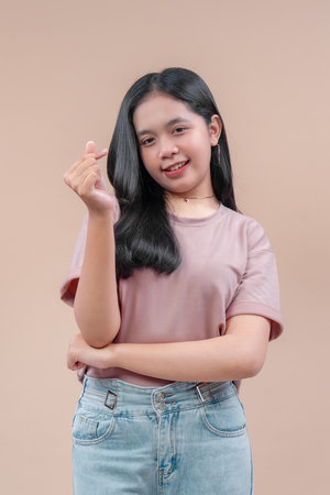 Asian woman with long black hair wearing casual t-shirt and jeans, smiling confidently while making...