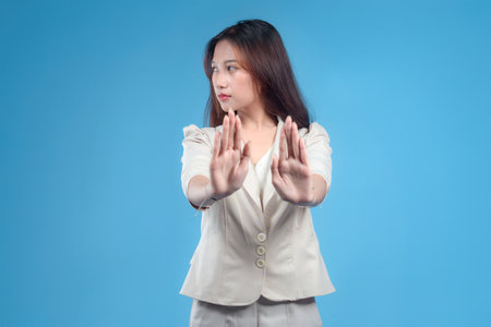 A confident Indonesian businesswoman making a two-hand stop gesture while looking aside, wearing formal attire and presenting a strong and professional image suitable for global corporate and business themes.の写真素材