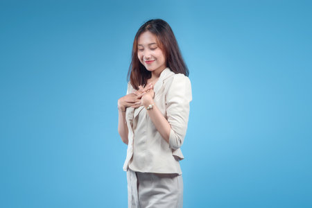 A confident Indonesian businesswoman smiling gently with her hands placed on her chest, dressed in formal attire and presenting a warm, elegant, and professional image suitable for global corporate and business themes.の写真素材