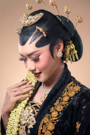 Indonesian woman in elegant Javanese bridal attire, bowing softly with ornate accessories, refined makeup, and detailed kebaya that highlights rich cultural heritage.の写真素材