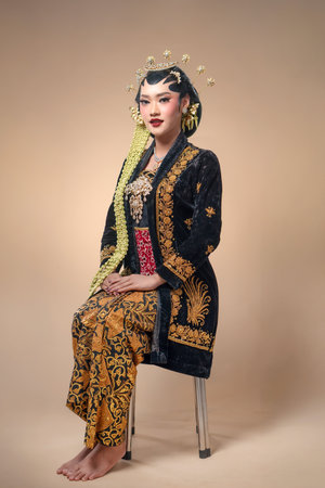 Indonesian woman in full Javanese bridal attire, featuring paes makeup, jasmine garlands, gold embroidery, and poised posture that reflects cultural elegance and refined tradition.の写真素材