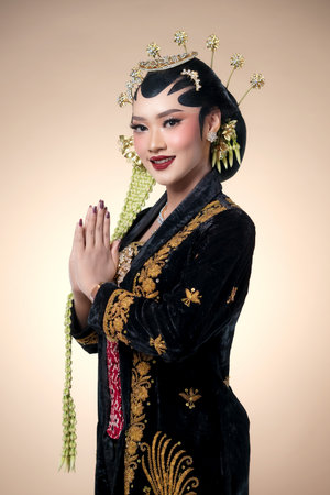 Indonesian woman in traditional Javanese bridal attire, showing a graceful greeting pose with paes...