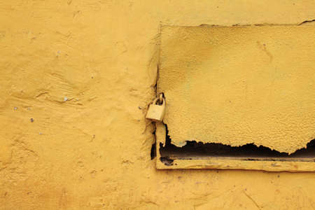 Abstract image of a yellow lock on an old yellow shelfの写真素材